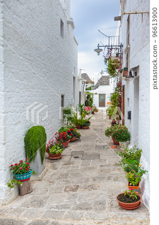 Beautiful town of Alberobello with Trulli houses among green plants and flowers, Apulia region, Southern Italy. 96613900