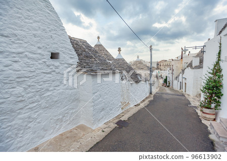Beautiful town of Alberobello with Trulli houses among green plants and flowers, Apulia region, Southern Italy. 96613902