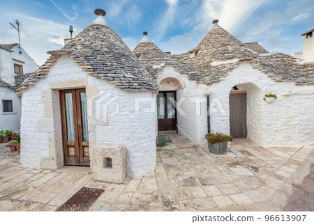 Beautiful town of Alberobello with Trulli houses among green plants and flowers, Apulia region, Southern Italy. 96613907
