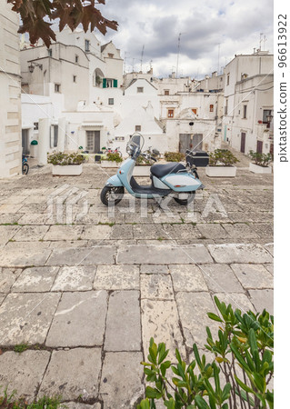 View of the old town of Martina Franca. Classic blue moped on the background of an anient buildings. 96613922