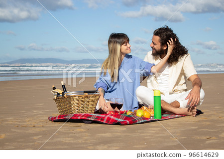 Beautiful young couple having picnic on the beach Beautiful young couple having picnic on the beach 96614629