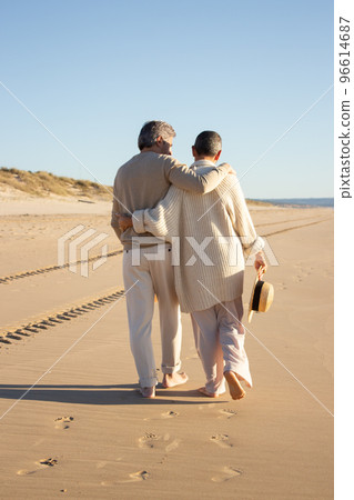 Senior couple walking barefoot on the beach 96614687