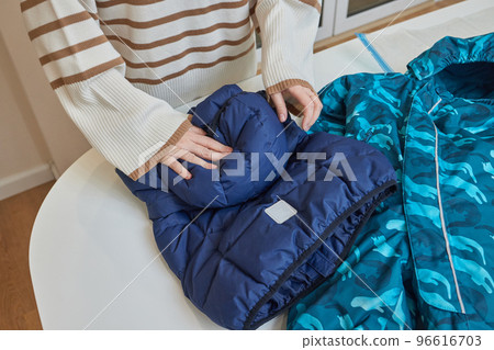 The girl pumps out air with a vacuum cleaner from a vacuum bag with clothes. The concept of storage and transportation of clothing, things. Space saving seal bag. The girl pumps out air with a vacuum cleaner from a vacuum bag with clothes. The concept of storage and transportation of clothing, things. Space saving seal bag. 96616703