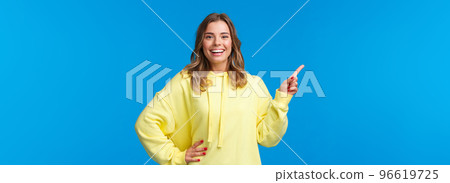 Take a look. Upbeat good-looking blond girl pointing finger left, recommend promo, advertise product, look pleased and smiling camera, explain project, standing blue background Take a look. Upbeat good-looking blond girl pointing finger left, recommend promo, advertise product, look pleased and smiling camera, explain project, standing blue background 96619725
