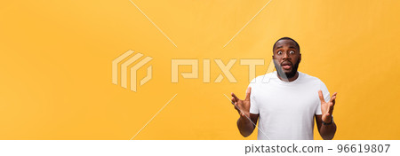 Portrait of african american man with hands raised in shock and disbelief. Isolated over yellow background. 96619807