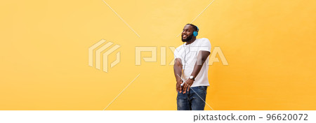 Full length portrait of a cherry young african american man listening to music with headphones and dancing isolated over yellow background 96620072