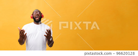 Young African American man wearing headphone and enjoy music over yellow gold Background Young African American man wearing headphone and enjoy music over yellow gold Background 96620128