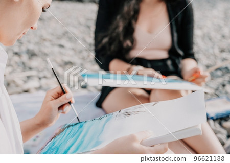 Unrecognizable woman's hands holding her own sea beach scenery watercolor painting. Amateur painter. Creative female artist drawing the picture at the beach. Art, creativity and inspiration concept. 96621188