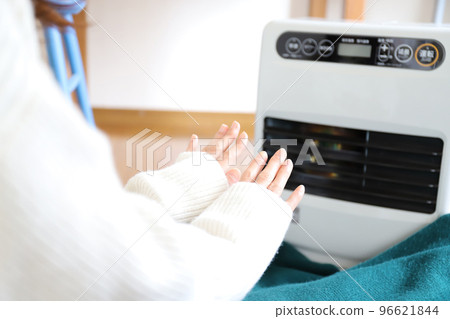 A woman who warms up with a fan heater A woman who warms up with a fan heater 96621844