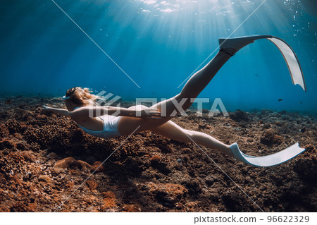 Woman freediver swim with fins over corals. Freediving in blue ocean Woman freediver swim with fins over corals. Freediving in blue ocean 96622329