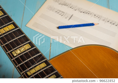 Music recording scene with guitar, music sheet and pencil on wooden table Music recording scene with guitar, music sheet and pencil on wooden table 96622852