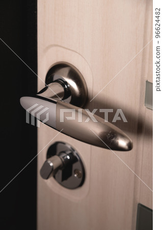 Close up of stylish silver chrome door handle on modern interior door. Stylish light brown door with frosted glass inserts. Concept of catalog of door handles for furniture store Close up of stylish silver chrome door handle on modern interior door. Stylish light brown door with frosted glass inserts. Concept of catalog of door handles for furniture store 96624482