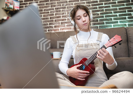 cute girl concentrated on playing the ukulele sitting on the floor at home cute girl concentrated on playing the ukulele sitting on the floor at home 96624494