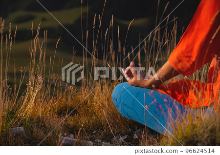 close-up of a woman's hand sitting in a meditation pose and holding mudra with fingers, yoga in the grass close-up of a woman's hand sitting in a meditation pose and holding mudra with fingers, yoga in the grass 96624514