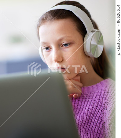 Distance learning concept. Adolescent schoolgirl studying online using laptop making notes in copybook. Teen girl school student wearing headphones watching internet video course sitting at home desk. 96626614