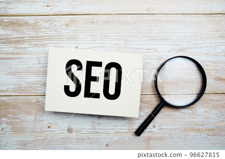 SEO text message and magnifying glass with space copy on wooden background 96627815