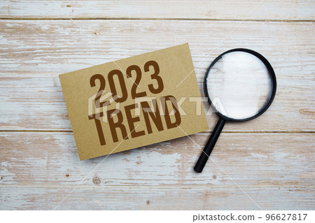 Trend 2023 text message and magnifying glass with space copy on wooden background 96627817