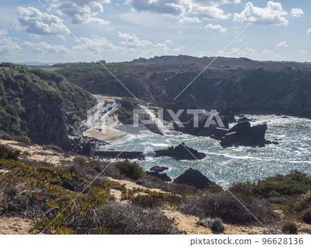 View of the small anchorage bay with fishing port at Azenha do Mar from the surrounding cliffs Odemira, Portugal. Sunny day, Clear blue sky. 96628136