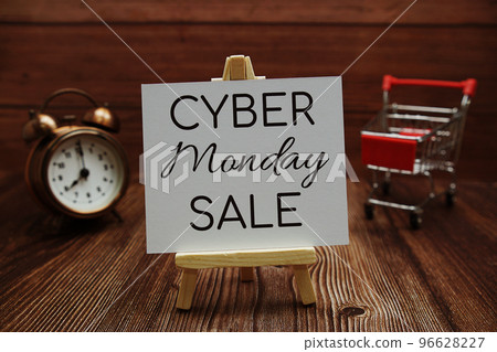 Cyber Monday Sale text on paper card with alarm clock and trolley cart on wooden background 96628227