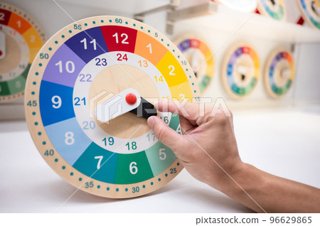 Male hand rotating clock pointer on colorful wooden clock Male hand rotating clock pointer on colorful wooden clock 96629865