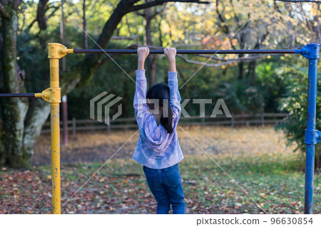 小學女生在秋季公園玩單槓 小學女生在秋季公園玩單槓 96630854