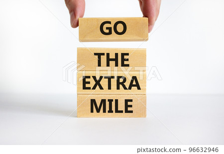 Go the extra mile symbol. Concept words Go the extra mile on wooden blocks. Businessman hand. Beautiful white table, white background, copy space. Business and go the extra mile concept. 96632946