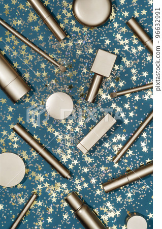 Luxury composition with golden cosmetic products and star shape confetti on dark teal background. Holiday background. Beauty concept. Luxury composition with golden cosmetic products and star shape confetti on dark teal background. Holiday background. Beauty concept. 96632991