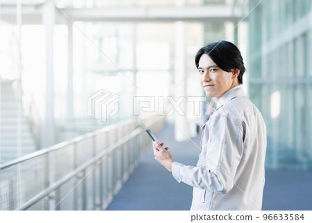 Young male engineer using smartphone Young male engineer using smartphone 96633584