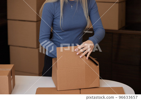 Caucasian girl taping boxes for moving in new apartment. Caucasian girl taping boxes for moving in new apartment. 96633657