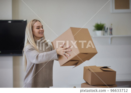 Caucasian girl taping boxes for moving in new apartment. Caucasian girl taping boxes for moving in new apartment. 96633712