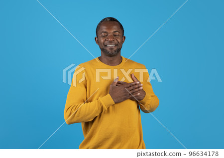 Peaceful african american man holding hands over his heart Peaceful african american man holding hands over his heart 96634178