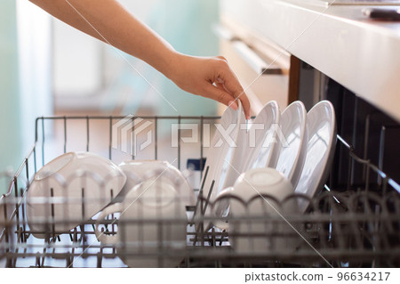 Closeup Shot Of Female Hand Loading Dishes To Dishwasher Machine In Kitchen Closeup Shot Of Female Hand Loading Dishes To Dishwasher Machine In Kitchen 96634217