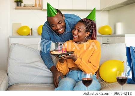 Husband's birthday. African american wife surprising husband with birthday cake, man enjoying b-day celebration at home 96634218
