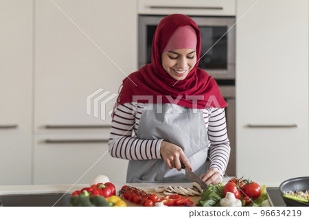 Cheerful middle eastern muslim woman preparing healthy meal at home 96634219