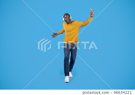 Positive energetic black man with headphones listening to music 96634221