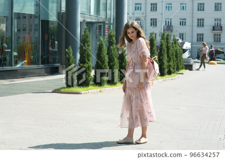 Portrait of a beautiful girl with a curly hair, smiling, looking away on the street. Walking around the city in the summer day. High quality photo 96634257