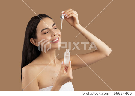 Close up portrait of beautiful half-naked woman using face oil Close up portrait of beautiful half-naked woman using face oil 96634409