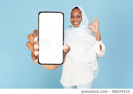 Excited black muslim woman showing phone blank screen and gesturing okay, space for website or app design, mockup 96634410