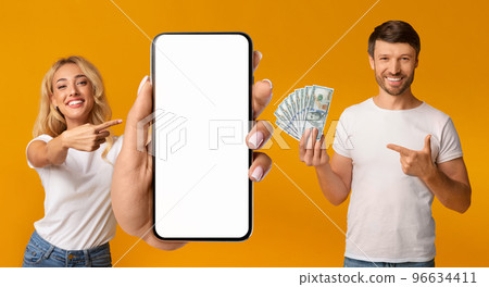 Beautiful couple gambling on Internet, using smartphone on orange, mockup 96634411