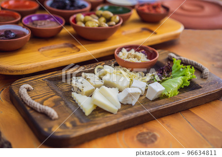 Turkish breakfast cheese. Pastries, vegetables, greens, olives, cheeses, fried eggs, spices, jams, honey, tea in copper pot and tulip glasses, wide composition 96634811