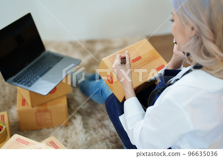 Starting small business entrepreneur of independent Asian woman smiling using computer laptop with cheerful success of online marketing package box items and SME delivery concept. 96635036