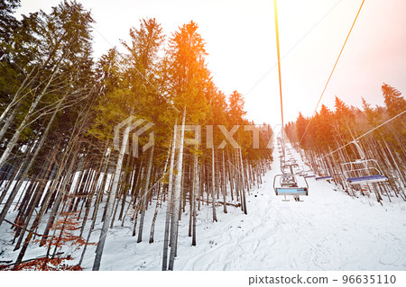 Ski lift at ski resort Bukovel in the mountains on a sunny winter day. Sun flare Ski lift at ski resort Bukovel in the mountains on a sunny winter day. Sun flare 96635110