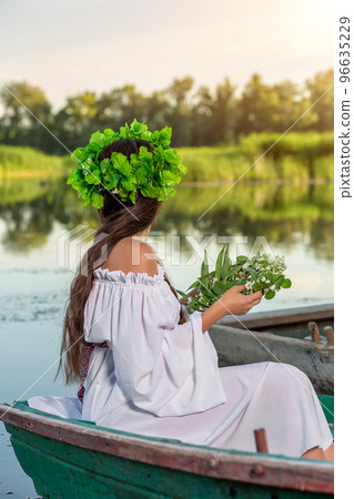 The nymph with long dark hair in a white vintage dress sitting in a boat in the middle of the river. The nymph with long dark hair in a white vintage dress sitting in a boat in the middle of the river. 96635229
