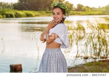 Young beautiful caucasian woman standing at the bank of river. Traditional countryside picture with girl at foreground and copy space. Young beautiful caucasian woman standing at the bank of river. Traditional countryside picture with girl at foreground and copy space. 96635447