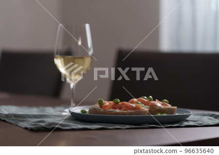 Bruschettas with cream cheese and salmon with glass of white wine on dining table Bruschettas with cream cheese and salmon with glass of white wine on dining table 96635640