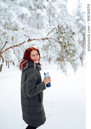 Cheerful girl in warm clothes playing with snow outdoors near the beautiful forest 96636059