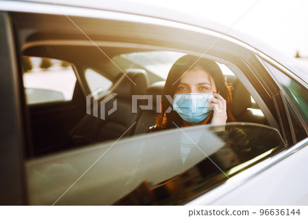 Girl in protective sterile medical mask on her face is talking on his phone in taxi. Covid-19 96636144