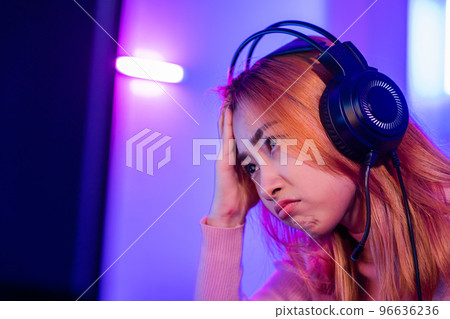Game Over. Asian gamer playing online video game she losing and sad on computer PC colorful neon LED lights, young woman in gaming headphones feeling disappointed about lost game, E-Sport concept Game Over. Asian gamer playing online video game she losing and sad on computer PC colorful neon LED lights, young woman in gaming headphones feeling disappointed about lost game, E-Sport concept 96636236