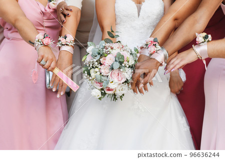 A bride with a bouquet and bridesmaids in identical dresses and bracelets 96636244