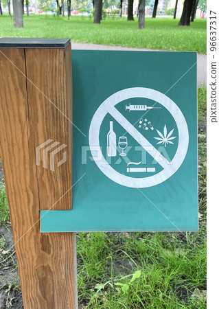 Sign prohibiting alcohol, cigarettes, drugs on background of green grass in park. Symbol on metallic plate. Sign prohibiting alcohol, cigarettes, drugs on background of green grass in park. Symbol on metallic plate. 96637317